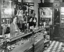 Interior view of Moss Jewellers, Amherst, NS, ca. 1949. Leon Moss can be seen in the background, one of two men standing under the luggage sign.; Courtesy of the Town of Amherst
