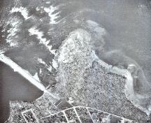 General view of Pointe-du-Buisson National Historic Site of Canada, showing the site’s setting on a point of land overlooking a vast area of rapids, with water along most of its perimeter.; Government of Quebec / Gouvernement du Québec.