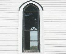 This image illustrates the wooden clapboard exterior and the narrow single lancet window with moulding on the side of a transept.; PNB 2005