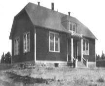 Ancienne photo de l'école, prise du côté sud-est, illustrant les fenêtres doubles donnant sur chaque salle de classe ainsi que sur le grenier; Memramcook Valley Historical Society