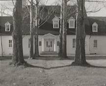 General view of Governors' Cottage, showing its formal, pillared, classically inspired entry porch, 1973.; Agence Parcs Canada / Parks Canada Agency, 1973.