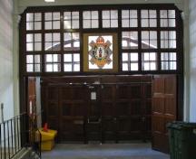 Vue intérieure du manège militaire, qui montre l’ancien emblème héraldique des armoiries du régiment arborant un sanglier au-dessus de l’entrée principale, 2006.; R. Goodspeed, 2006.