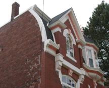 This side view image shows the convex roof, the Greek Revival gable dormer and the oriel window; City of Saint John
