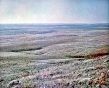 Vue générale du cairn du British Block, qui montre son emplacement dans une région de prairie vallonnée des grandes plaines, couverte de végétation mixte.; Parks Canada Agency / Agence Parcs Canada, Harry A. Tatro.