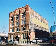 This image illustrates the front, west-facing brick-clad facade of the HV Shaw Building showing the elaborate Chicago School-influenced decorations and the south elevation with its painted signs.; City of Edmonton, 2004