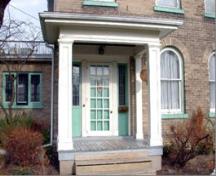 Featured is the portico, pillars and multi-pane storm door flanked by sidelights.; City of Brantford, n.d