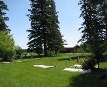 View of cemetery with Metis cabin in background, 2009.; Ross Herrington, 2009.