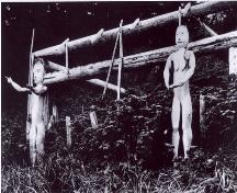 Historic image of two welcome figures in front of a house at Kiix?in village, ca. 1905.; Parks Canada Agency / Agence Parcs Canada, 1905.
