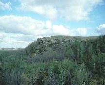 Distance view of the outcrop where the petroglyphs are located, 1993.; Government of Saskatchewan, 1993.