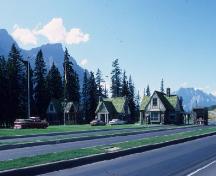 View of the East Gate Registration Buildings, with Building 3 on the left, showing the manner in which the East Gate Registration Buildings reinforce the picturesque character of their mountain park setting, 1985.; Parks Canada Agency / Agence Parcs Canada, 1985.