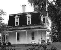Side view of the Superintendent's Residence, showing the two-storey massing with a four-sided mansard roof with overhanging eaves and gabled dormers, 1972.; Parks Canada Agency / Agence Parcs Canada, 1972.