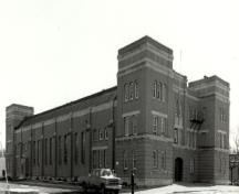 Corner view of the McGregor Street Armoury, showing the monumental scale and massing consisting of a principal block, sturdy, square corner towers, 1994.; Department of National Defence / Ministère de la Défense nationale, 1994.