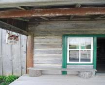 Post Office's front entrance, surrounded by original log; board and batten siding visible on left; Photographs taken by Dana Johnson, May 4th, 2010, with permission of  the Oil Museum of Canada