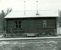 Front elevation of the N.W.M.P Married Officers' Quarters, showing the log construction of peeled local spruce logs, sawn on three sides and lapped at the corners, 1987.; Agence Parcs Canada / Parks Canada Agency, 1987.