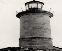 Vue générale du phare, qui montre la volumétrie, soit la tour circulaire et la plate-forme en béton de la lanterne surmontée d’une coupole.; National Archives of Canada / Archives nationales du Canada.