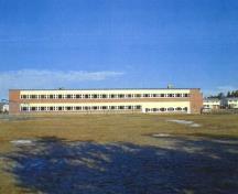Vue de l'arrière de l'école MacKenzie, qui montre sa volumétrie compacte et simple de deux étages revêtu de brique rouge-orange.; Department of National Defence / Ministère de la Défense nationale.