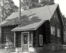 Vue de l'arrière de la résidence du gardien, qui montre le plan rectangulaire du bâtiment, avec un porche à l’avant et un toit à deux versants, couvert de bardeaux et percé d’une cheminée, 1984.; Parks Canada Agency / Agence Parcs Canada, S. Siepman, 1984.