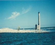 Vue en angle du Phare à l'île Mohawk, où l'on peut apercevoir les qualités pittoresques de la conception et de la forme, qui se voient dans la hauteur du phare par rapport au terrain plat de l’île, 1987.; Department of the Environment / Ministère de l'Environnement, 1987.