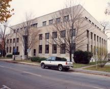 General view of the Government of Canada Building, showing its exterior walls of limestone masonry faced with stone of different types for decorative effect, 1991.; Department of Public Works / Ministère des Travaux publics, 1991.