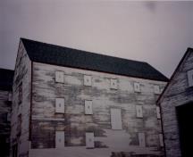 Façade latérale de l'entrepôt de poissons Ryan, qui montre les murs en bardage à clin agrémentés par des moulures aux proportions fines, 1993.; Agence Parcs Canada / Parks Canada Agency, 1993.