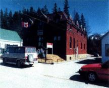 Vue en angle de l'Édifice du Gouvernement du Canada de Sherbrooke, qui montre le briquetage aux détails architecturaux modestes, la fondation en béton et les appuis de fenêtre en pierre, 1998.; Parks Canada Agency / Agence Parcs Canada, KAL, 1998.