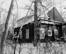 Vue en angle de la résidence Troberg, qui montre le caractère domestique de son emplacement retiré, avec ses arbres plantés, 1988.; Agence Parcs Canada / Parks Canada Agency, 1988.