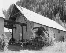 Vue en angle de l'entrepôt 2, qui montre la forme et volumétrie simples d’entrepôt, y compris le toit à deux versants, 1988.; Agence Parcs Canada / Parks Canada Agency, 1988.