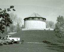 General view of Murney Martello Tower, showing its profile and massing consisting of the circular tower sitting on a parapet, 1991.; Parks Canada Agency / Agence Parcs Canada, Fern Graham, 1991.