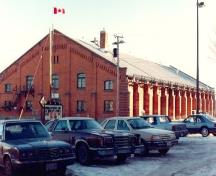 Corner view of the Armoury in Pembroke, showing its load bearing exterior walls clad in red brick with engaged pilasters, 1992.; Department of National Defence / Ministère de la Défense nationale, 1992.