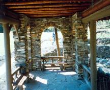 Interior view of the Cambrian Pavilion, showing the stone flagged floor and the plank benches with burl specimens, 1997.; Parks Canada Agency / Agence Parcs Canada, 1997.