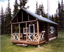Corner view of Isaac Creek Warden Cabin, showing the main entrance and the open porch projecting from the front, 1996.; Parks Canada Agency/ Agence Parcs Canada, 1996.