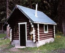 View of the Jacques Lake Warden Cabin Tack Shed; showing the main entrance, side façade and the gabled roof with chimney.; Parks Canada Agency/ Agence Parcs Canada, 1996.