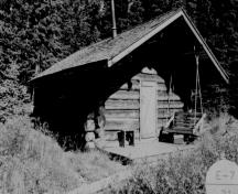 General view of Creek Cabin, showing its simple and plain massing as a single-room gable-roofed cabin, 1994.; Agence Parcs Canada / Parks Canada Agency, 1994.