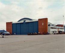 Vue générale du hangar 2 démontrant les ouvertures larges et hautes sur les façades est et ouest, surélevées au centre pour les avions particulièrement hauts et les structures en briques à chaque extrémité, 2000.; Department of National Defence / Ministère de la Défense nationale, 2000.