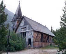Corner view of St. Andrew's Presbyterian Church, showing its simple rectangular wood frame structure with a gable roof and an adjoining asymmetrically placed tower, 1988.; Parks Canada Agency/Agence Parcs Canada, Chilkoot Trail National Historic Park, 1988.