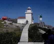 Vue générale du phare de West Point, qui montre la palette de couleurs, tel qu’observée dans l’usage de bardeaux rouge sur le toit à deux versants et de la couleur blanche sur la lanterne et la rambarde, 2006.; Fisheries and Oceans / Pêches et Océans Canada, 2006.