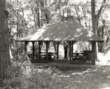 View of the Aubrey Island Picnic Shelter, showing the hipped roof, vertical wood supports and wood brackets, 1992.; Archaeological Services and Historica Resources, Ltd., 1992.