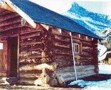 Corner view of the Halfway Hut showing the use of natural, local materials consistent with the principles of rustic architecture such as the horizontally laid peeled log construction, boulder foundation, and wood shingle roof.; Western Canada Service Center / Centre de services de l'Ouest canadien, n.d.