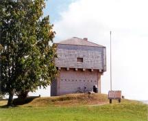 General view of the rear and side elevations of the St. Andrews Blockhouse showing the simple, well-proportioned, geometric massing of the squat square profile with a pyramidal roof, 1998.; Parks Canada Agency/ Agence Parcs Canada, 1998.