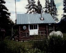 Side view of the Topaz Warden Patrol Cabin, showing the walls of peeled 8-10 inch logs, horizontally laid and saddle- notched at the corners, 1997.; Parks Canada Agency / Agence Parcs Canada, 1997.
