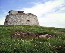 General view of the Carleton Martello Tower showing the simple geometric massing of the squat cylindrical tower, 1983.; Agence Parcs Canada / Parks Canada Agency, F. Catroll, 1983.