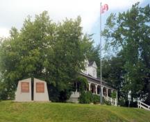 This image shows a side view of the Tilley House with the National Historic Sites of Canada monument in the foreground; Village of Gagetown
