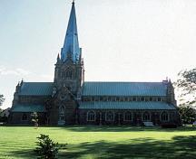 Vue de côté de la Cathédrale Christ Church, qui montre son emplacement pittoresque au milieu d'une grande pelouse.; Parks Canada Agency / Agence Parcs Canada.