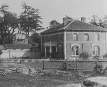 General view of the Admiral’s Residence and Former Naval Storekeeper’s House, showing the rectangular, two-storey form of the building executed in brick and stone.; British Columbia Archives and Records Service, / Archives et Service des documents de la Colombie-Britannique, HP 7856.