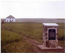 The Fort Pitt plaque erected by the Province of Saskatchewan in 1973 showing the reconstructed factor’s house in background; Parks Canada / Parcs Canada,