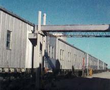 General view of Module Train B, showing its exterior metal cladding and the size, form and spacing of door and window openings dictated by each modules function, 1998.; Canada, North Warning System Office / Bureau du système d'alerte du Nord, 1998.
