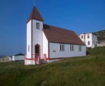 General view of Battle Harbour Historic District, St. James the Apostle Anglican Church with its rectangular, gable-roofed massing, clapboarding, two-stories and pyramidal tower, 2003.; Parks Canada Agency/Agence Parcs Canada, J. McQuarrie, 2003.