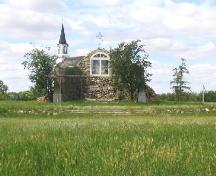 View northwest at fieldstone shrine (note iron cross on top of the grotto, replica; Government of Saskatchewan, Marvin Thomas, 2004.