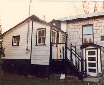 Vue générale de la façade est et la véranda de la maison fortifiée du maître-éclusier, 1987.; Parks Canada Agency / Agence Parcs Canada, 1987.