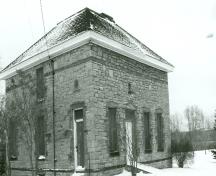 Vue de la façade principale du Bureau de la Gilmour and Hughson Limited, qui montre la volumétrie cubique sur deux étages, avec le toit en croupe tronqué, 1991.; Parks Canada Agency / Agence Parcs Canada, Jocelyne Cossette, 1991.